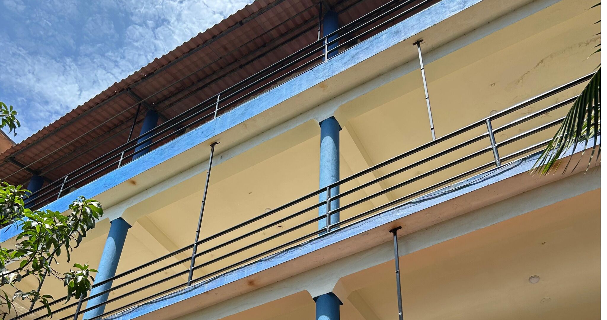 A multi-story building with a balcony, metal railings, and a red roof.