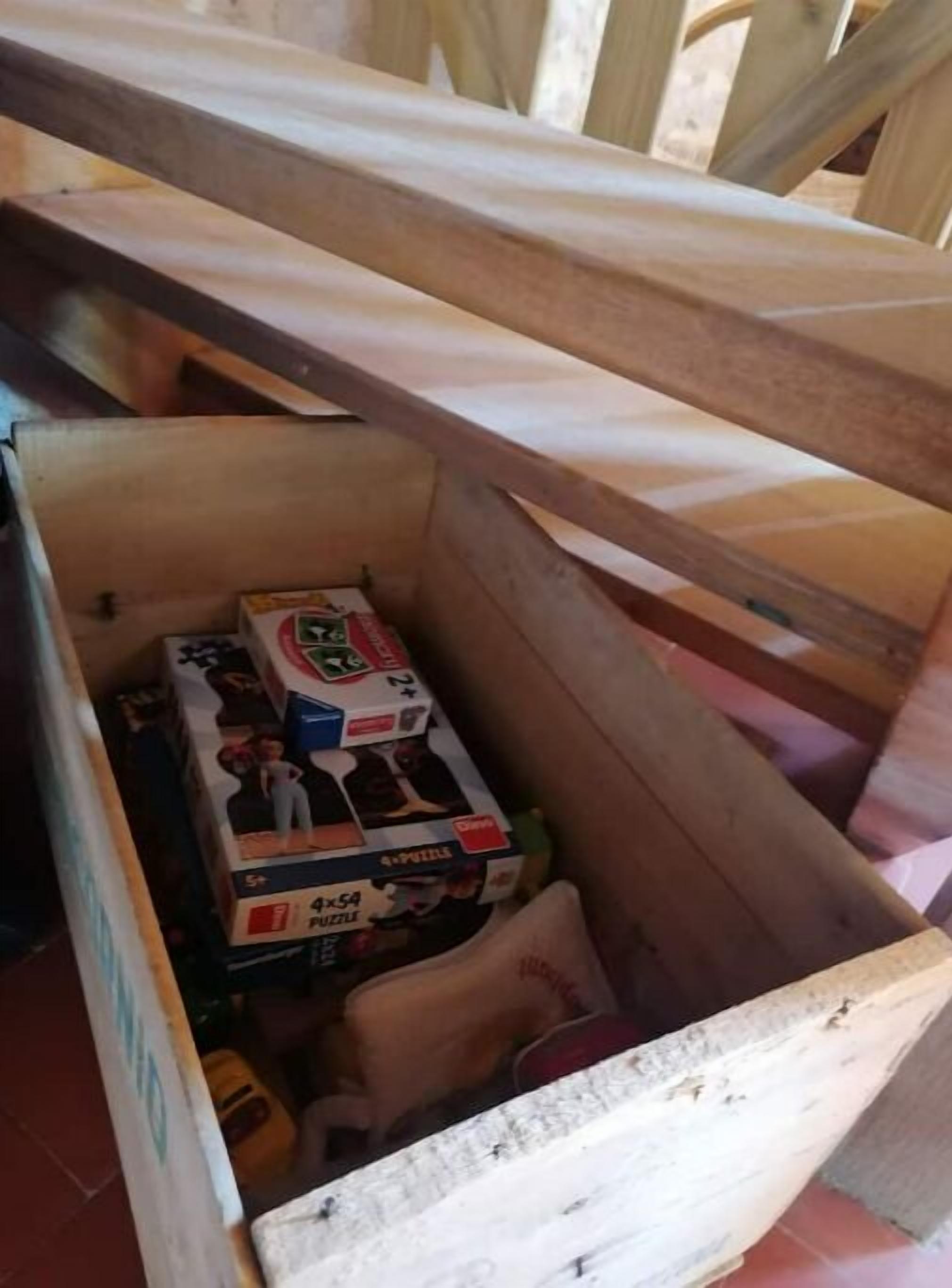 A wooden chest with a hinged lid, containing several items including a puzzle box and other small objects.