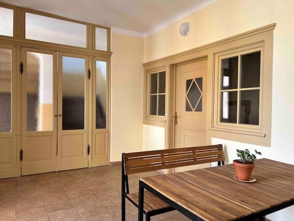 Enjoy a traditional dining experience in this cozy room, featuring a dining table and bench, a potted plant, and a window with a unique glass design.
