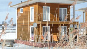 A wooden cabin with a balcony, a satellite dish, and a view of the water.