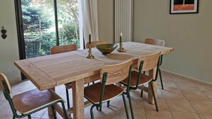 Un coin repas avec une table et des chaises en bois, un bol, des bougies et une œuvre d’art encadrée accrochée au mur.