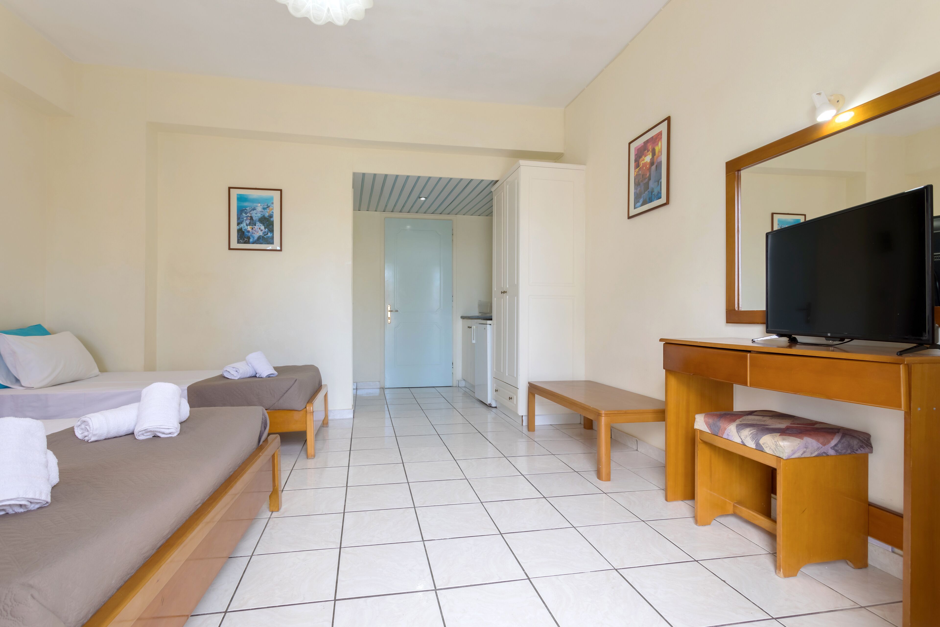 Une chambre d’hôtel avec un lit, un bureau avec une télévision et une salle de bain visible au fond.