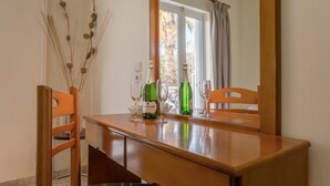 A dining area with a wooden table, chairs, and a window with curtains. - Laganas Holidays Hotel (Zakynthos)