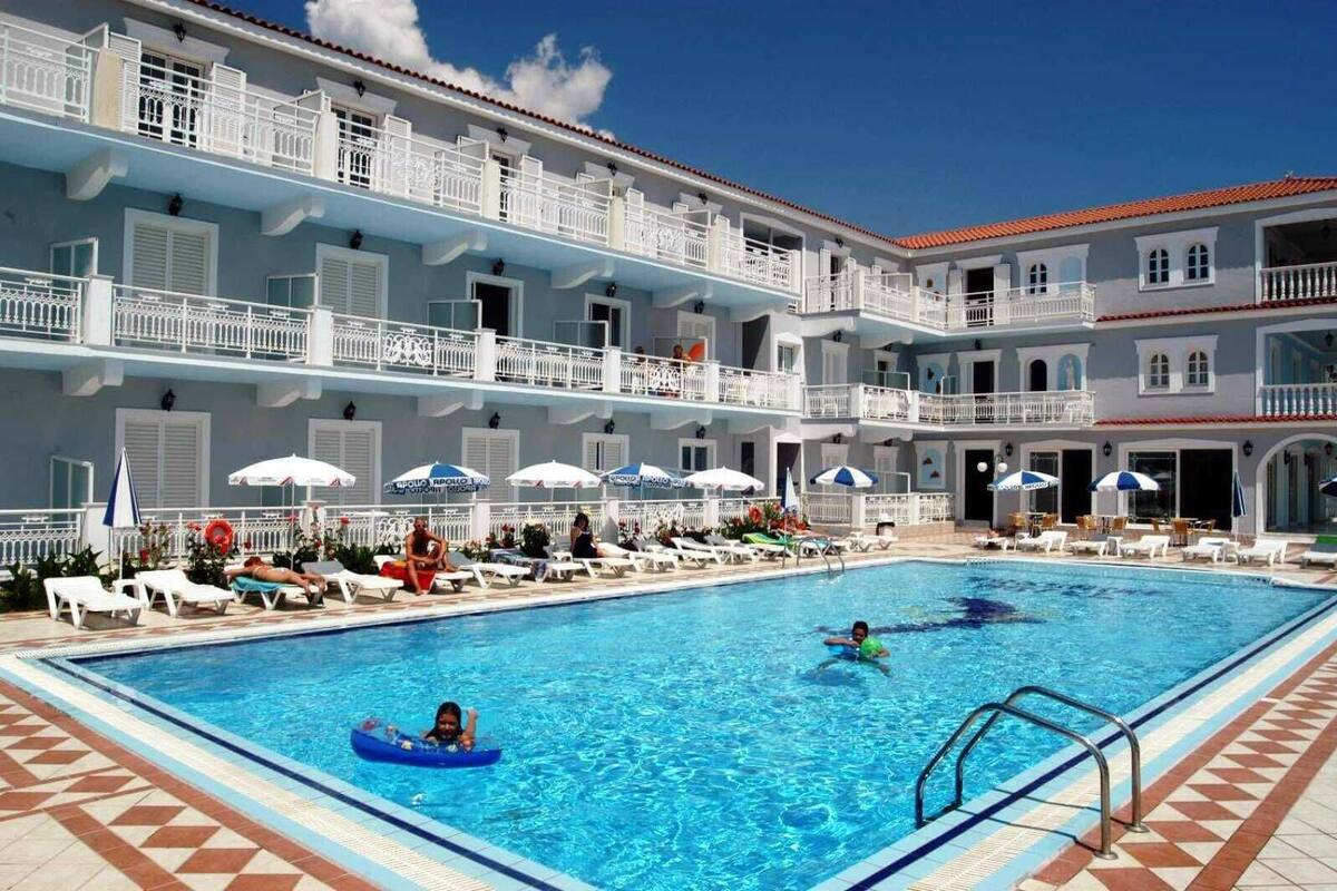 Área de piscina de hotel com vários níveis de varandas, espreguiçadeiras e guarda-sóis.