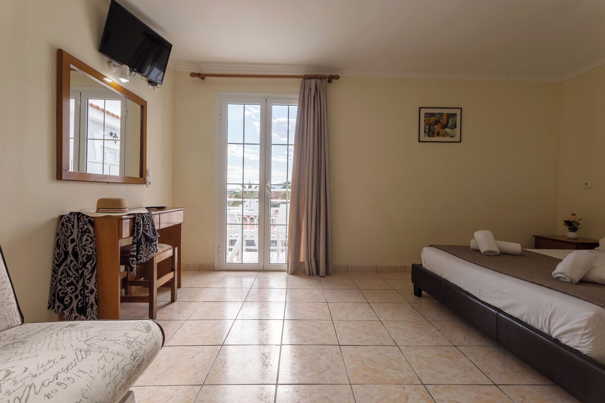 A hotel room with a bed, a desk, a chair, a television, and a window with curtains.