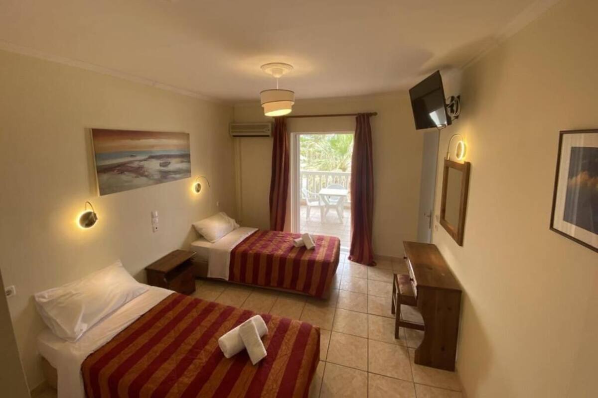 Quarto de hotel com duas camas, uma mesa, televisão e um quadro.