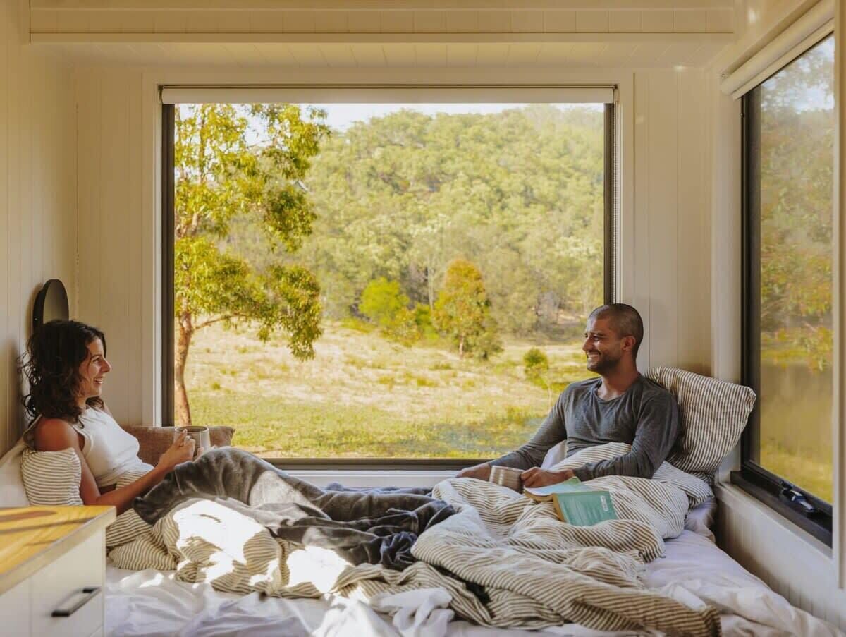 A room with a large window, a bed, and a bedside table.