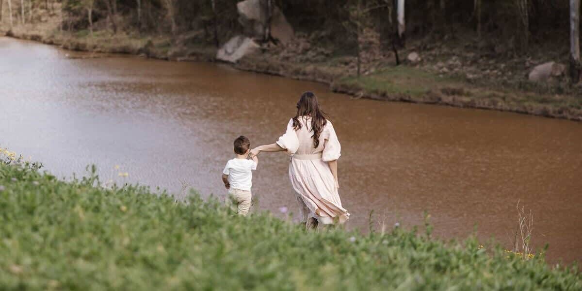 A woman and a child by a calm river.