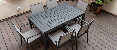 A patio with a rectangular table and six chairs.