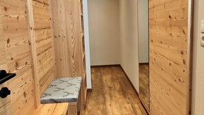 Un pasillo con paredes de madera y un banco, que conduce a un armario espejado.