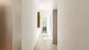 Un couloir étroit aux murs de couleur claire et au plancher en bois.