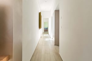 Un pasillo estrecho con paredes de tonos claros y suelo de madera.