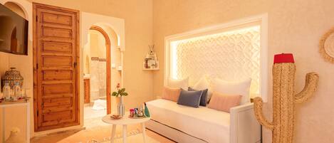 A cozy living room with a white sofa, a round coffee table, and a cactus decoration.