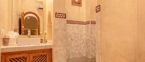 A bathroom with a sink, mirror, shower, and toilet.