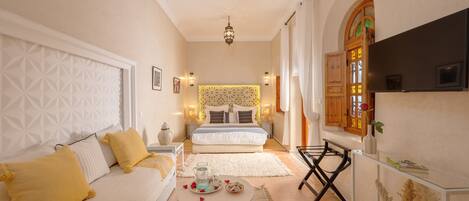 Une chambre à coucher comprenant un lit, des tables de chevet, un canapé, une table basse et un téléviseur.