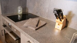 Een keukentafel met een opgevouwen handdoek, een glazen vaas en een messenblok.