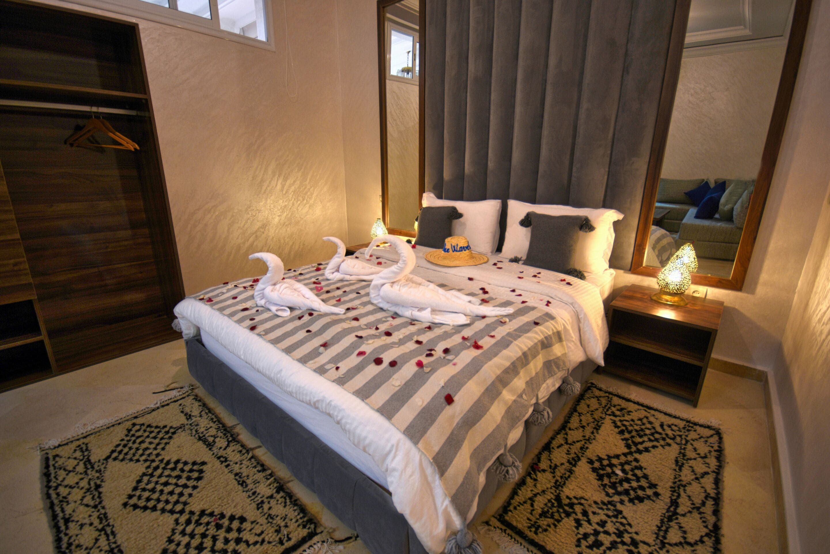 A neatly made bed with a striped bedspread, two pillows, and a bedside table with a lamp.