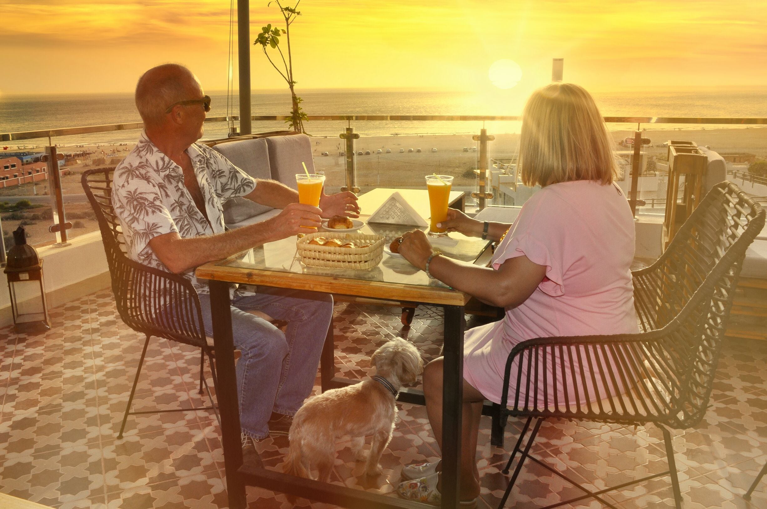 A couple dining at a table with a view of the sunset over the ocean.