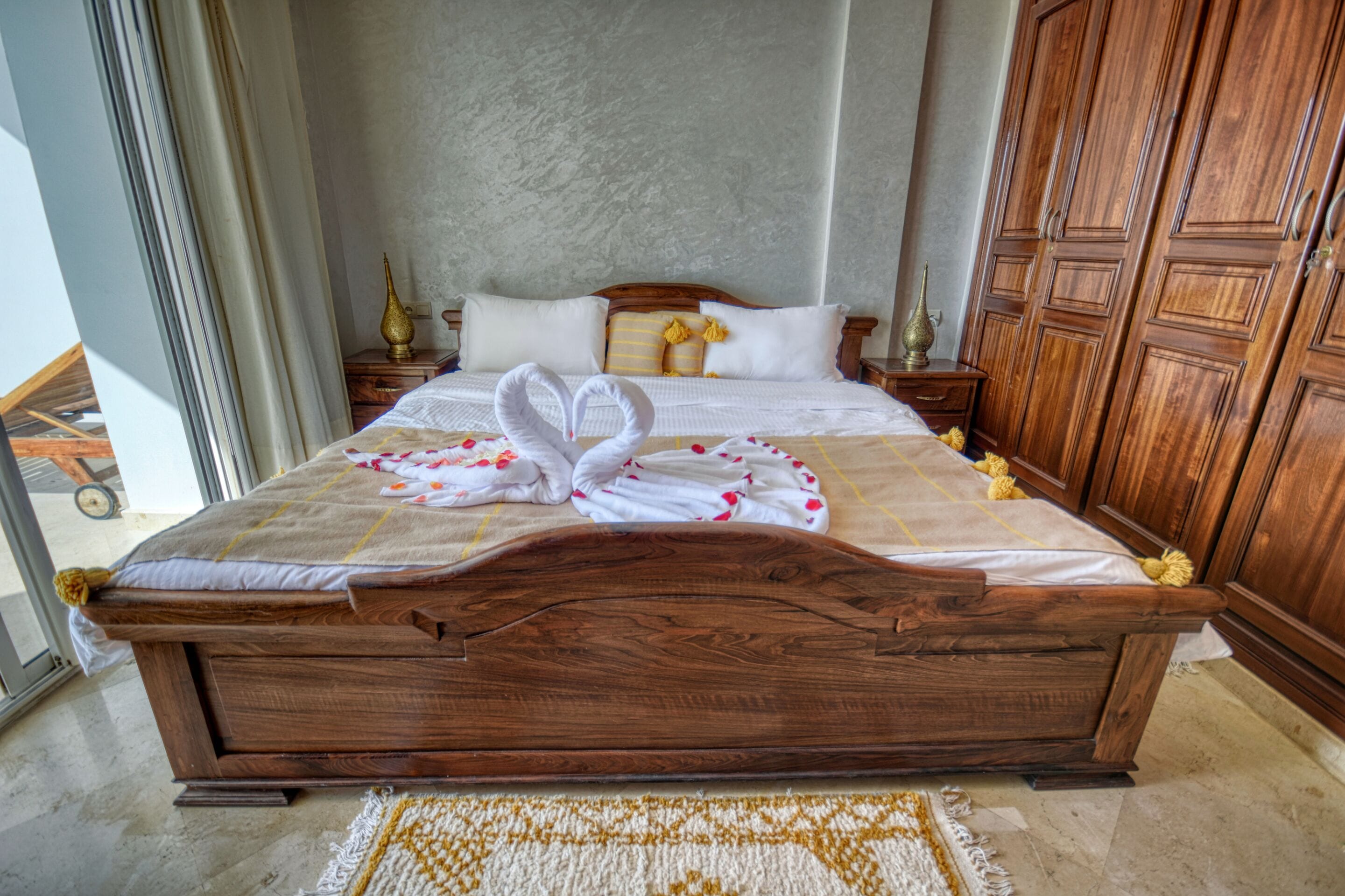 A large wooden bed with a headboard, white linens, and decorative pillows.