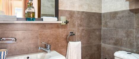 A bathroom with a sink, mirror, towel rack, and toilet.