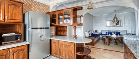 Una cocina con armarios de madera, un refrigerador de acero inoxidable y una encimera de mármol.