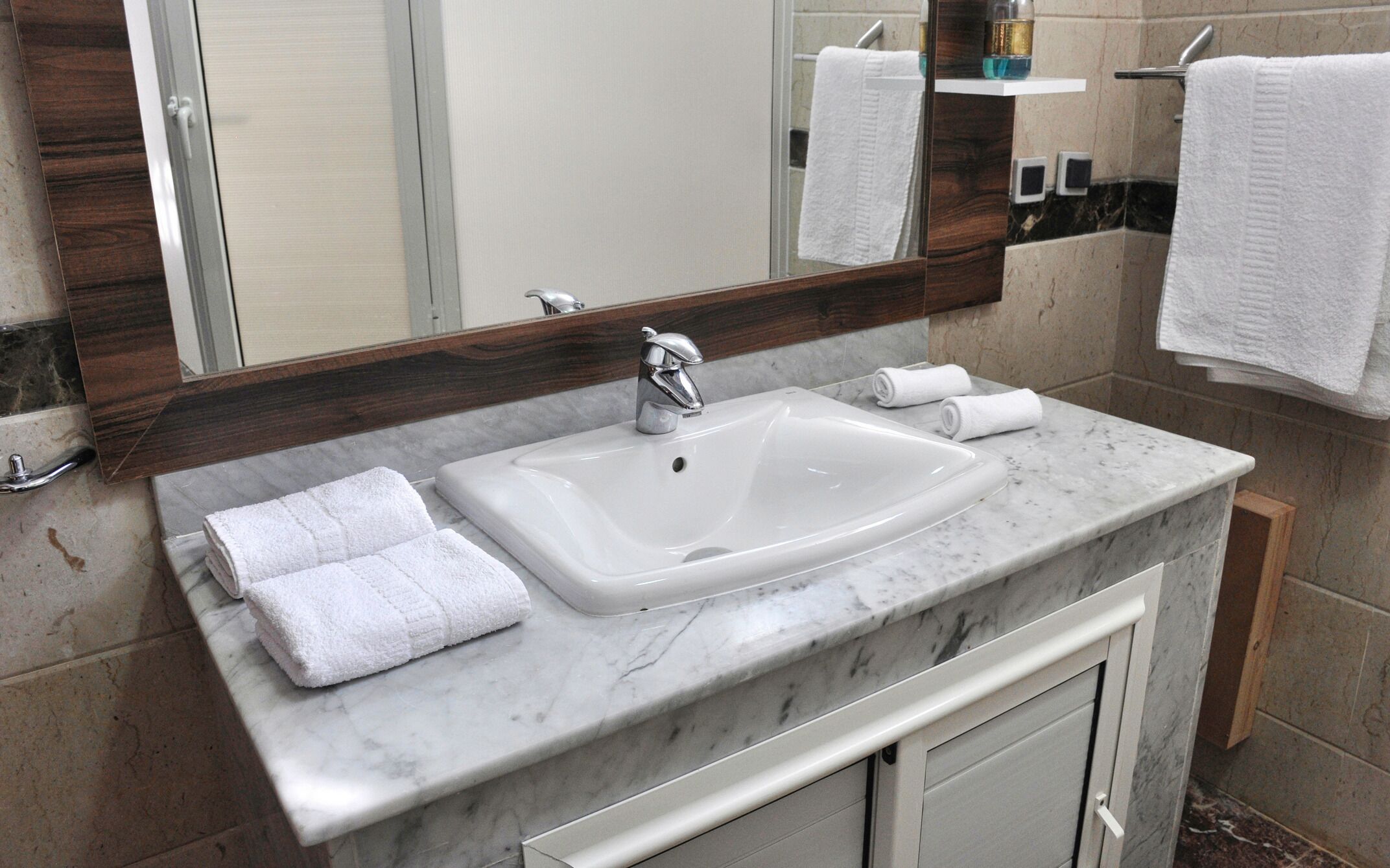A bathroom with a white sink, a mirror, and two towels on the counter.
