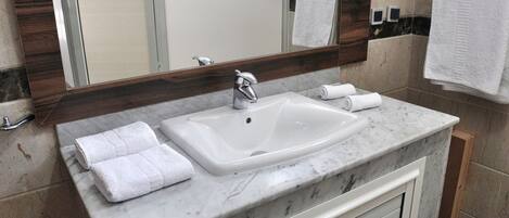 A bathroom with a white sink, a mirror, and two towels on the counter.