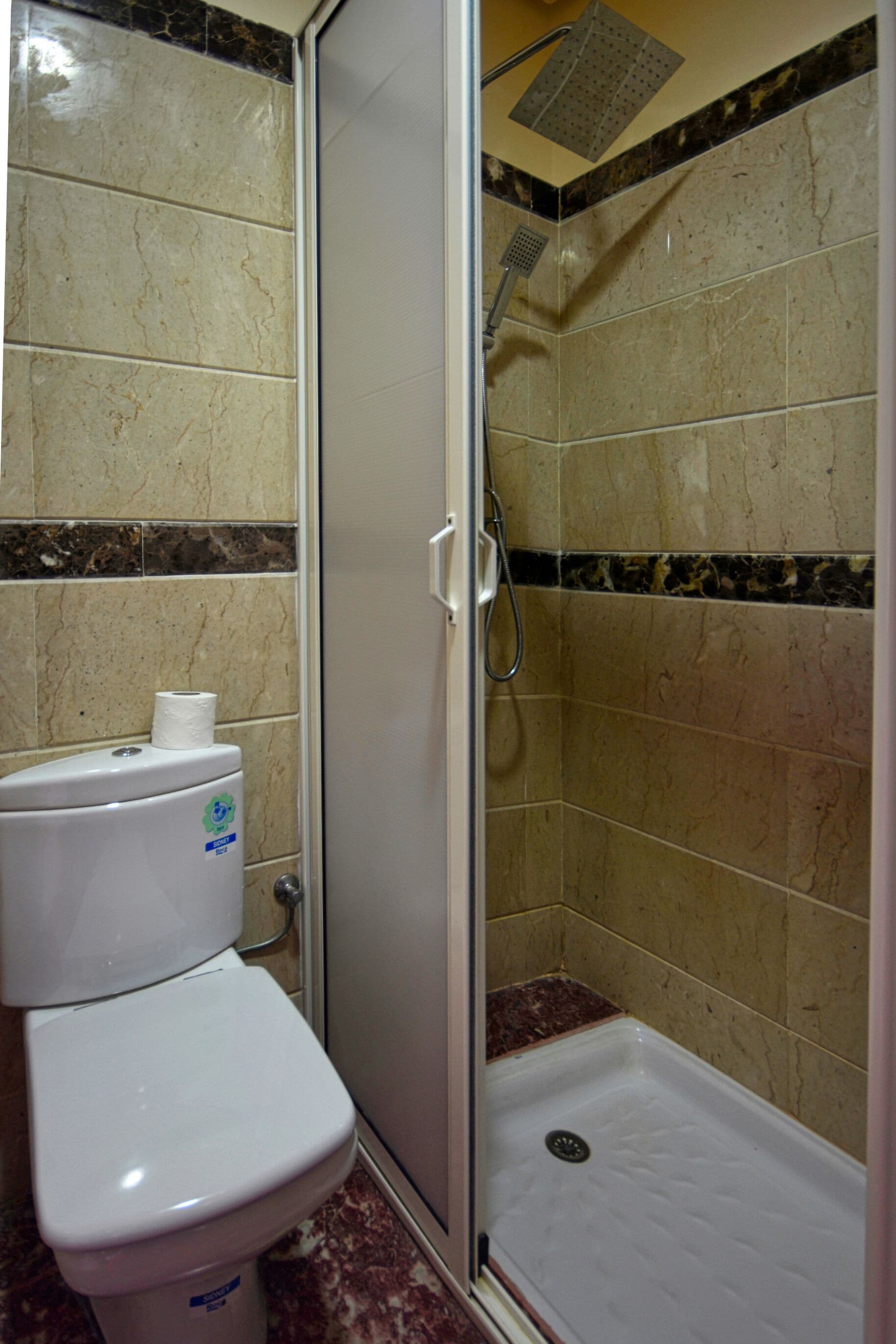 A bathroom with a toilet, a shower stall, and tiled walls.