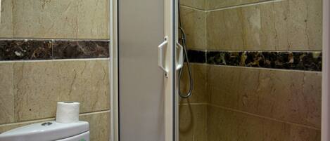 A bathroom with a toilet, a shower stall, and tiled walls.