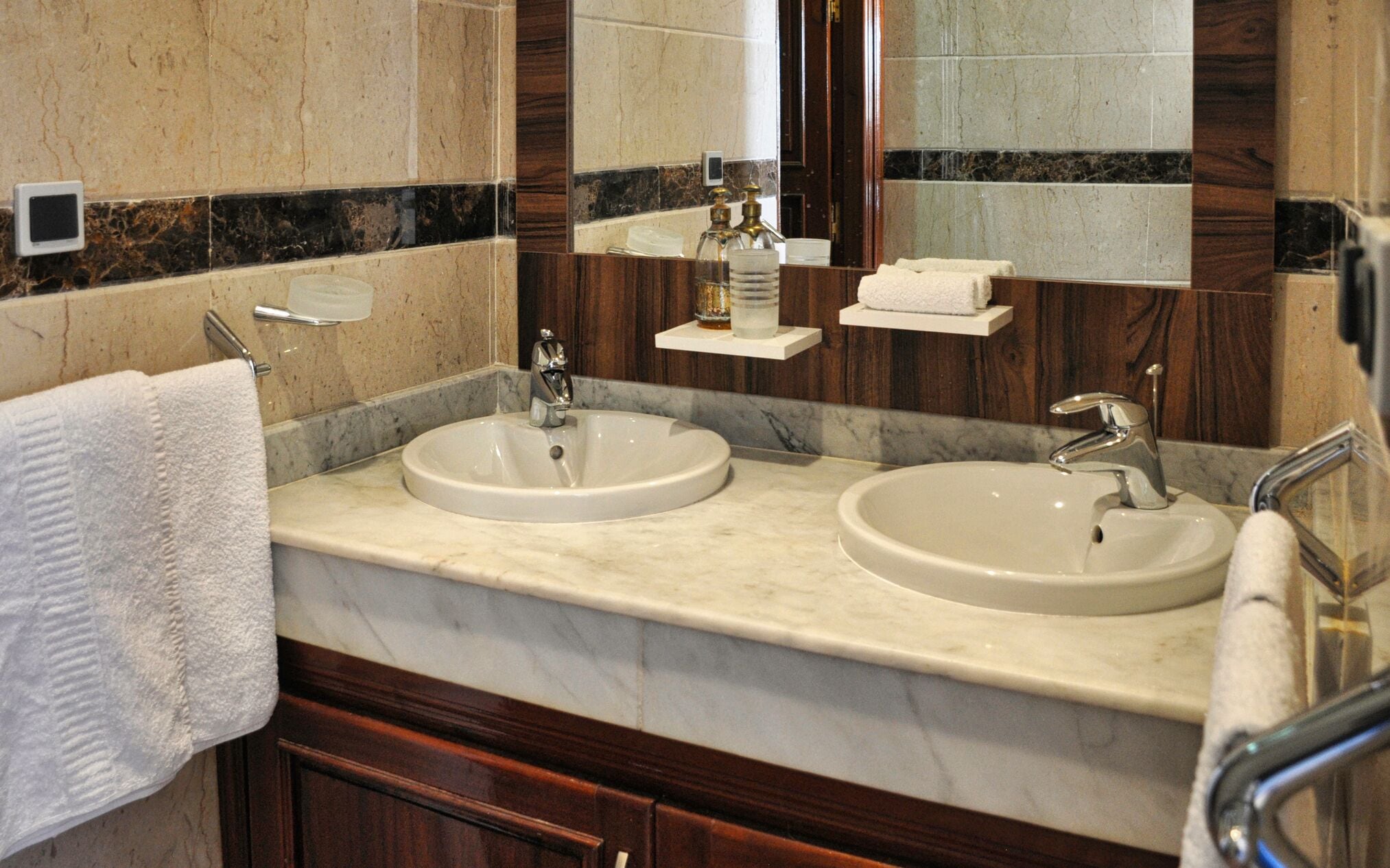 A bathroom with two sinks, a mirror, and a towel rack.