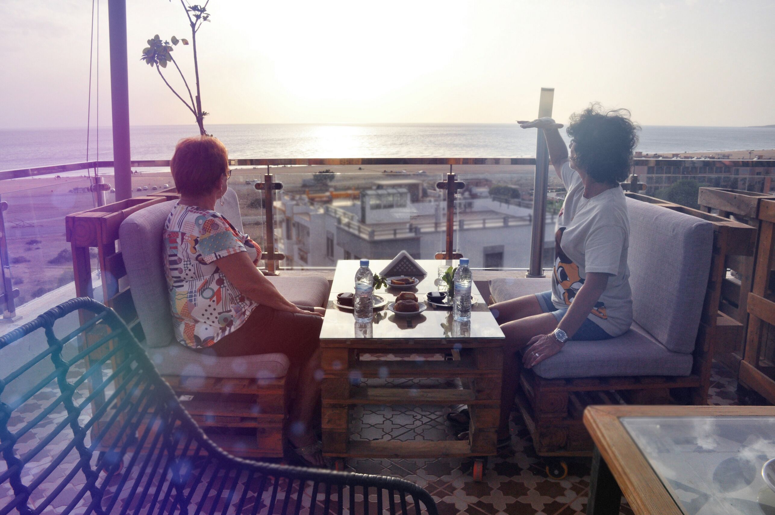 Ein Balkon mit Tisch für Zwei, mit Blick auf Stadt und Meer.