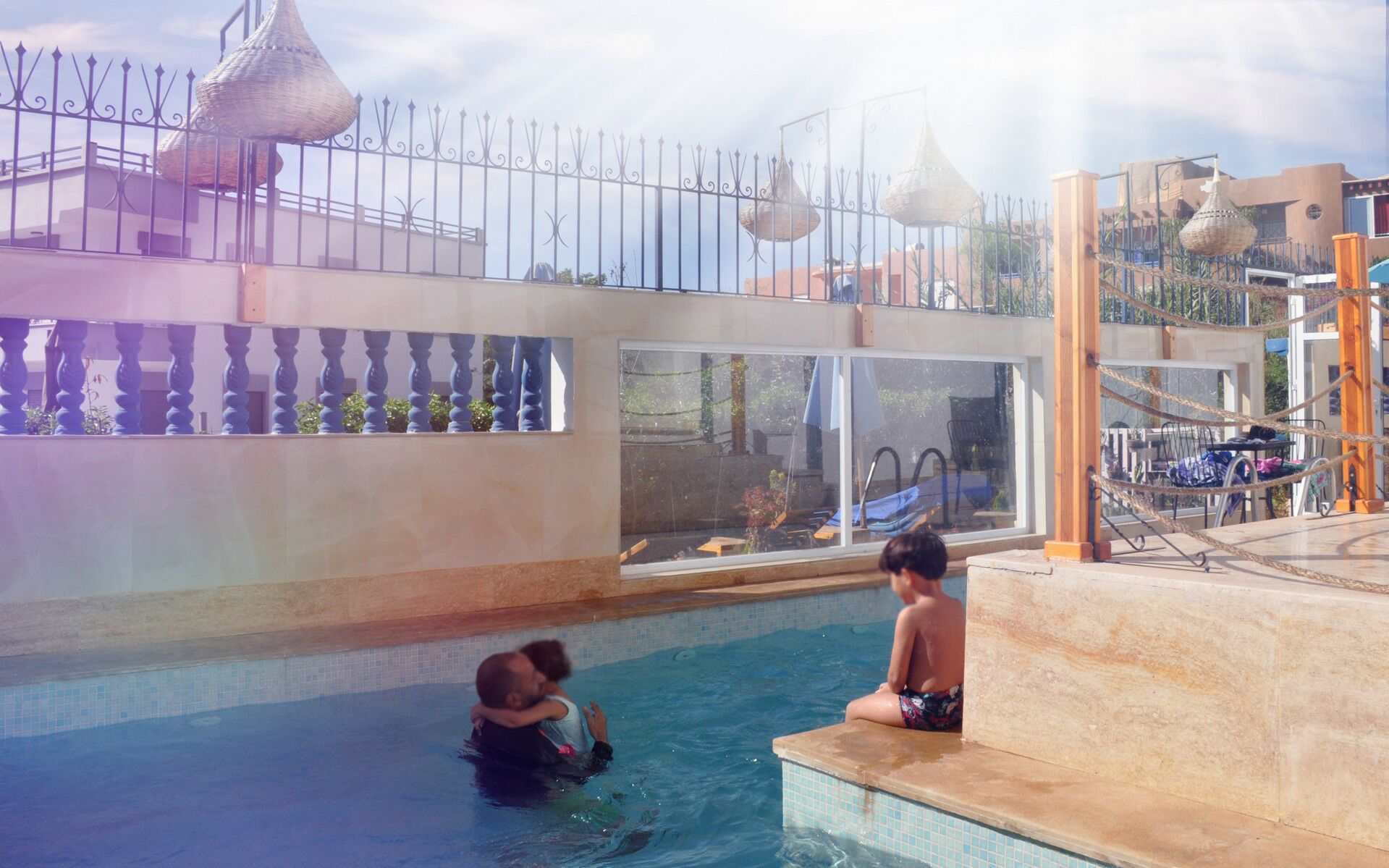 Zona de piscina con vistas a los edificios circundantes y un balcón con barandillas decorativas.