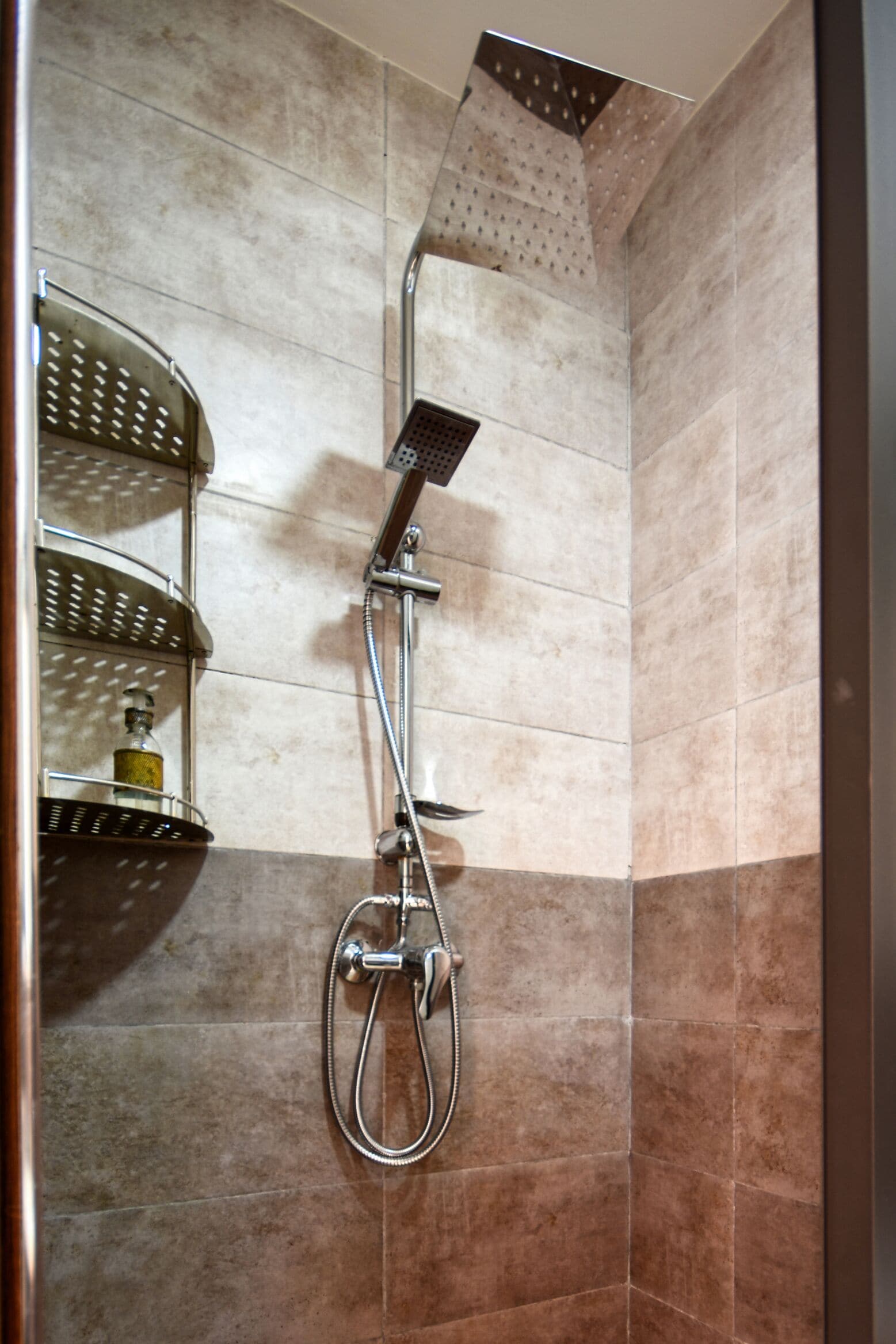 A shower with a handheld showerhead and a wall-mounted faucet.