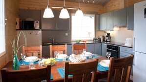 A wooden-paneled kitchen with a dining table set for four, featuring a microwave, stove, and cabinets.