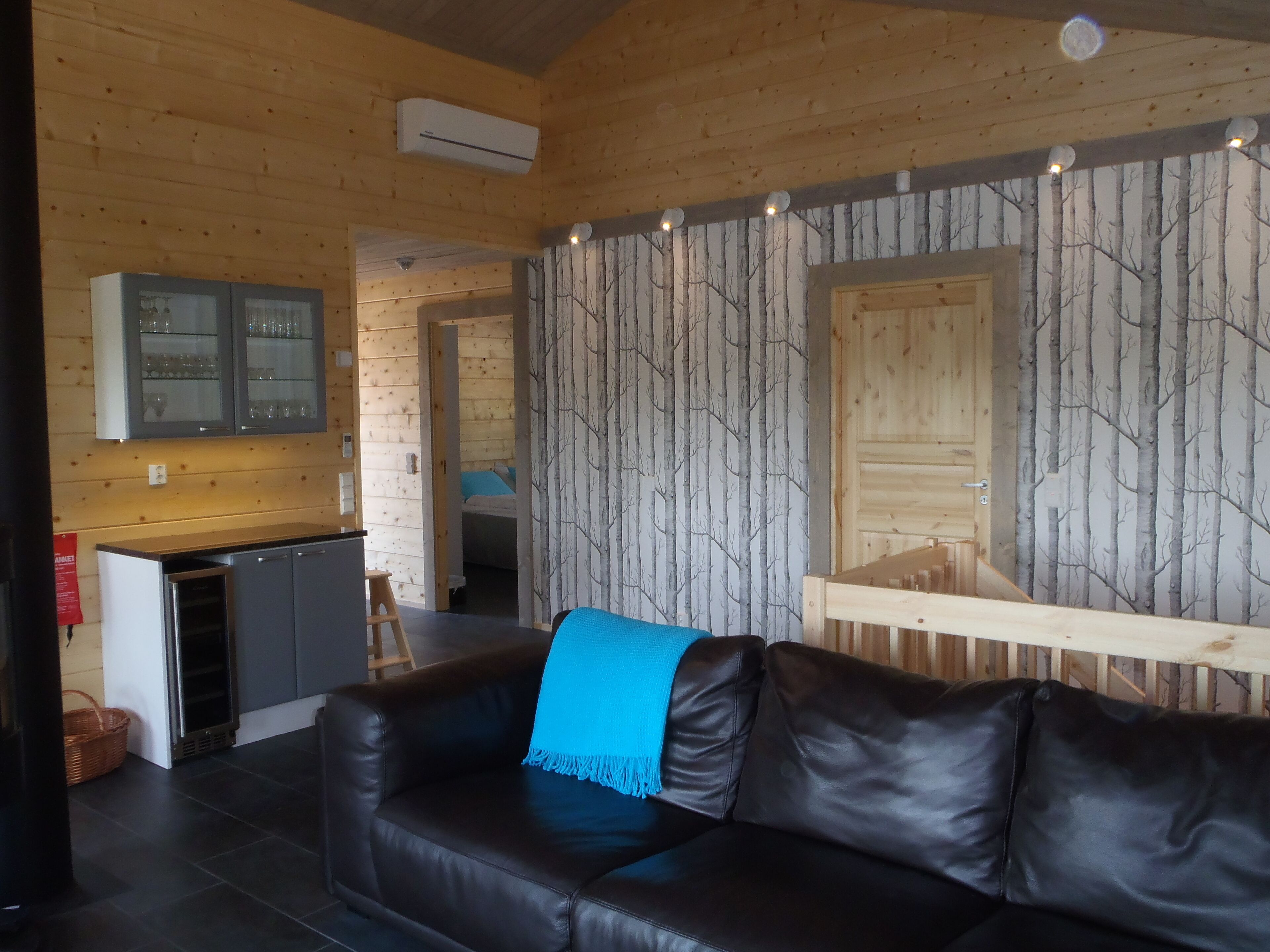 Ein gemütliches Blockhaus-Interieur mit Ledersofa, Küchenbereich und Essplatz.