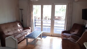 A living room with a brown sofa, a white coffee table, and a brown armchair.