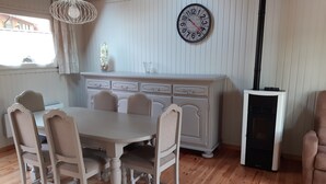 A dining area with a wooden table and chairs, a white cabinet, and a clock on the wall.