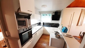 A compact kitchen with white cabinets, a black countertop, and a wooden floor.