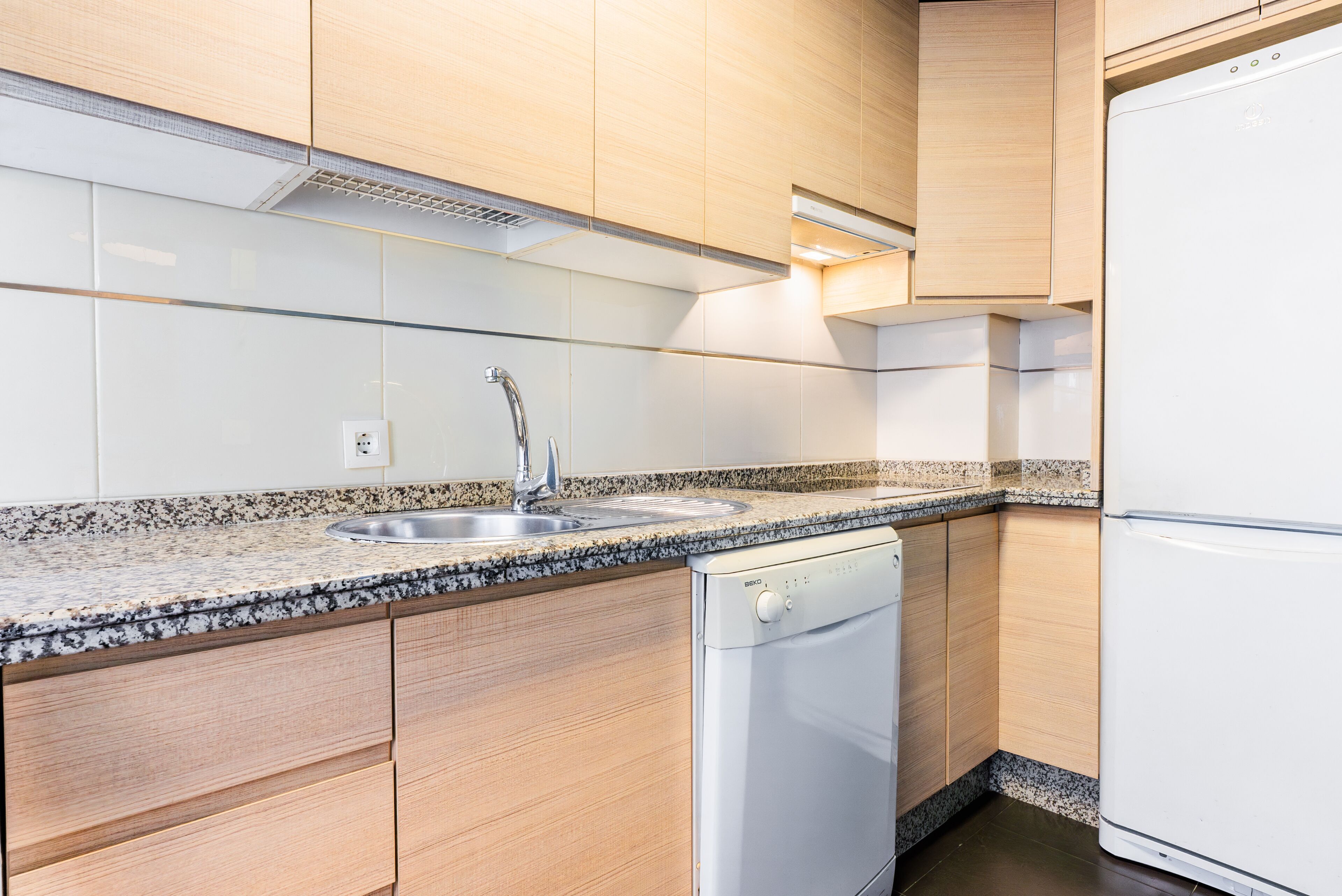 Eine moderne Küche mit Holdekor-Schränken, einer Granit-Arbeitsplatte, einem integrierten Geschirrspüler und einem weißen Kühlschrank.