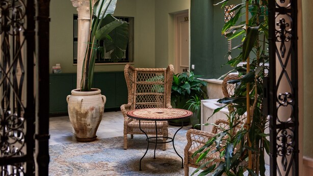 A courtyard with a wrought iron gate, a stone archway, wicker furniture, and potted plants. - Smartr Sevilla Las Dueñas (Seville)