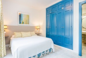 A bedroom with a large bed, a blue wardrobe, and two bedside lamps.