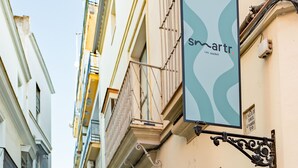 A narrow street with buildings on either side, a sign for 'smarttr' hotel, and a blue door with a number '11'. - Smartr Sevilla Las Dueñas (Seville)