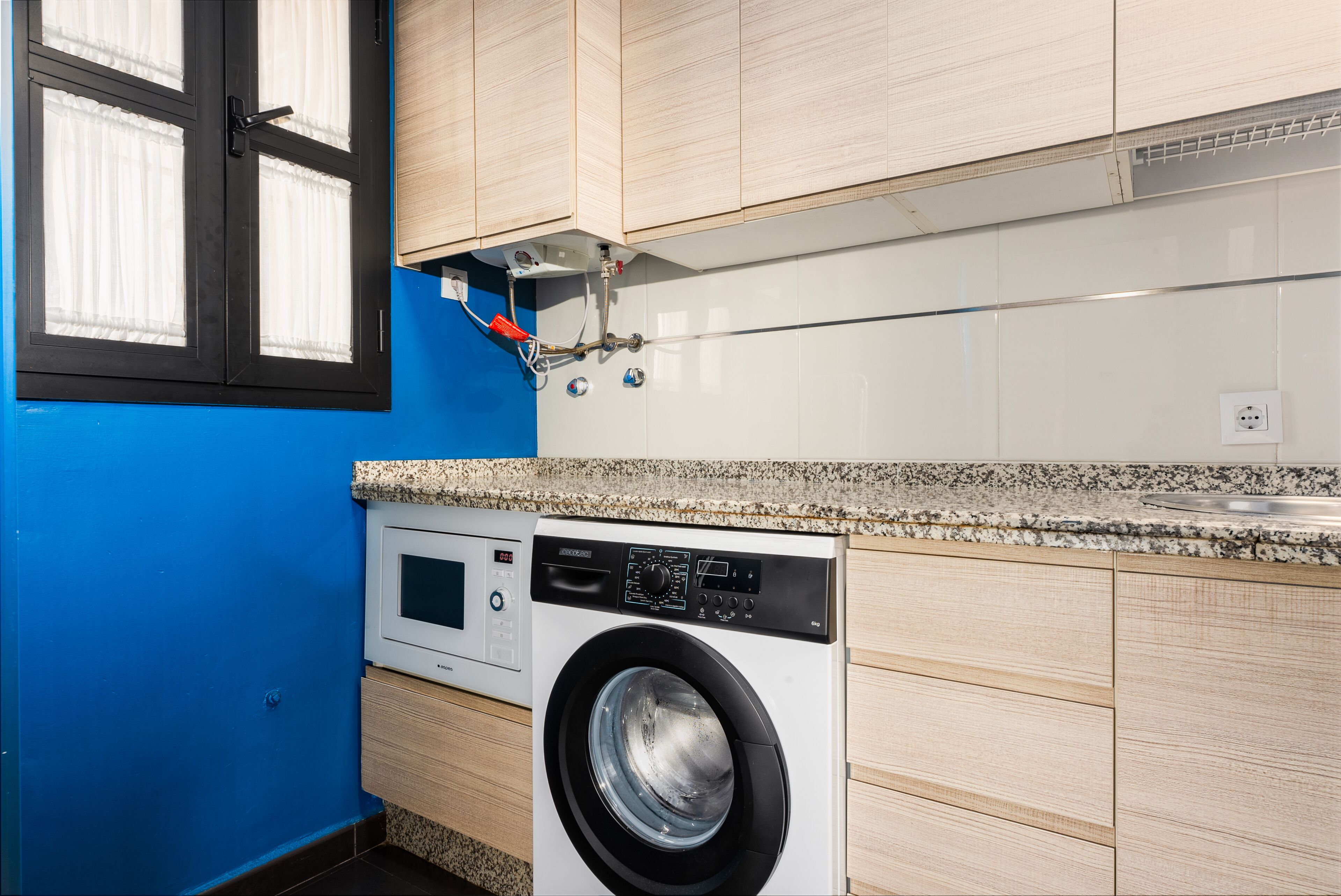 A compact laundry room with a washing machine, a dryer, and a small shelf with a power outlet.