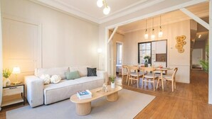 A spacious living room with a sofa, coffee table, and dining area. - Le Champagne Central (Reims)