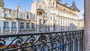 A view of a street with historic buildings, a metal fence, and a shop with a sign. - Le Champagne Central (Reims)
