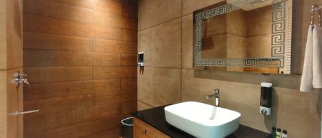A modern bathroom with a wooden wall, a white sink, and a mirror with a decorative frame.