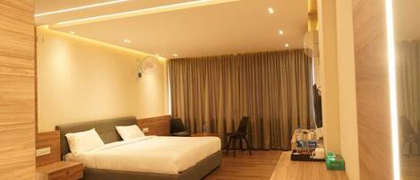 Una habitación de hotel moderna con una cama grande, un escritorio con silla y un televisor.