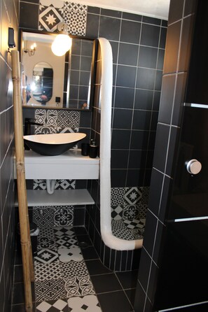 A bathroom with a black and white tiled floor, a white sink, and a mirror above it. - Vougli View (Mykonos)