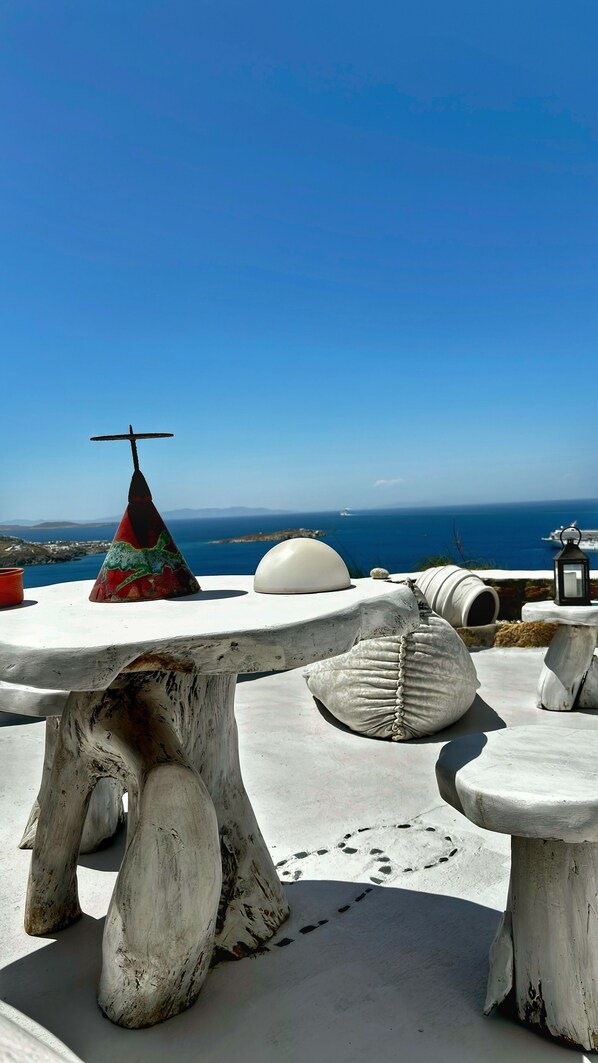 A table with a unique design, set against a backdrop of a clear blue sky and a distant view of the sea.