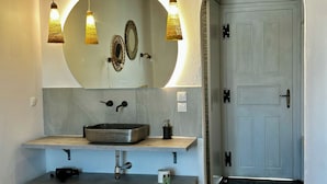 A modern bathroom with a large mirror, a vessel sink, and a wooden ceiling. - Vougli View (Mykonos)